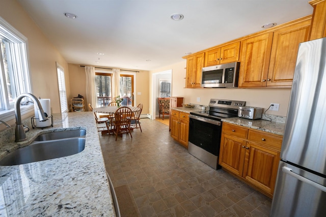 kitchen featuring a sink, light stone countertops, appliances with stainless steel finishes, and recessed lighting