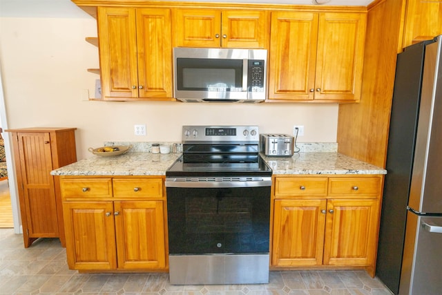 kitchen with light stone countertops, brown cabinets, and stainless steel appliances