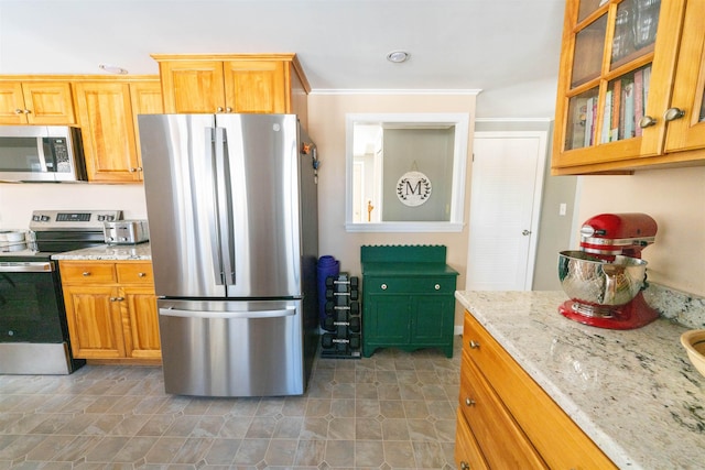 kitchen featuring light stone counters, stainless steel appliances, glass insert cabinets, and ornamental molding