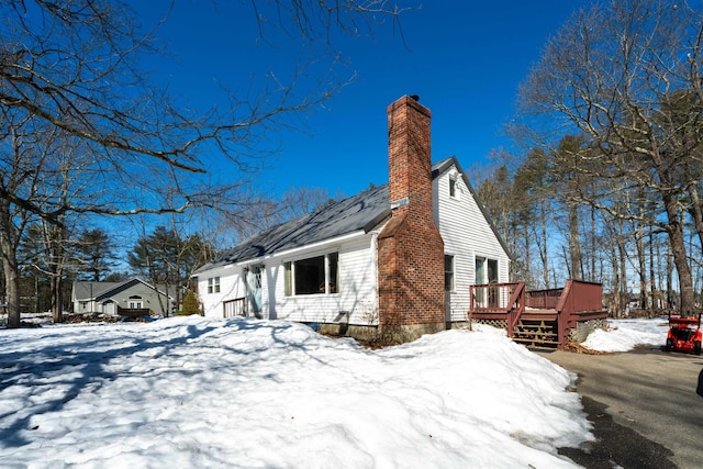 snow covered property with a chimney and a deck