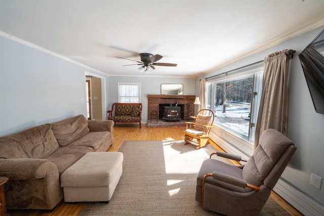 living area featuring crown molding, a wood stove, wood finished floors, and baseboard heating