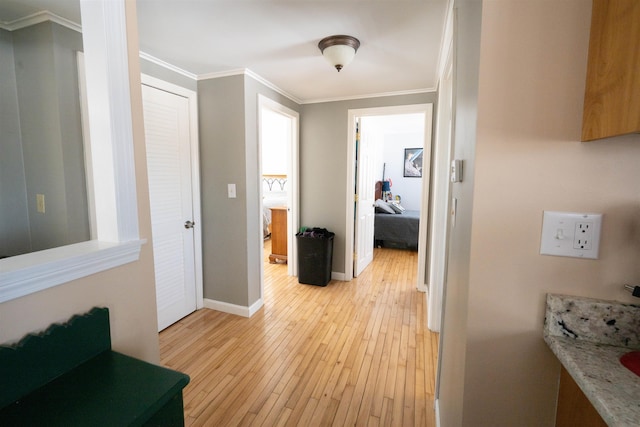 corridor featuring baseboards, light wood-style floors, and crown molding