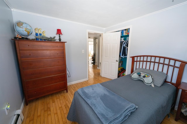 bedroom featuring a baseboard heating unit, baseboards, hardwood / wood-style floors, and ornamental molding