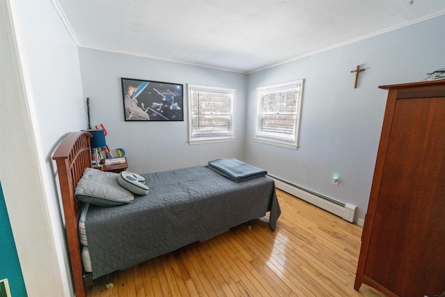 bedroom featuring a baseboard heating unit, hardwood / wood-style flooring, and crown molding