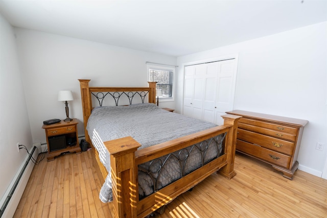 bedroom featuring light wood finished floors, baseboards, a closet, and a baseboard radiator