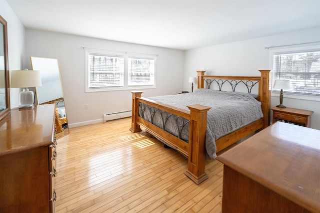 bedroom featuring multiple windows, baseboards, light wood-type flooring, and baseboard heating