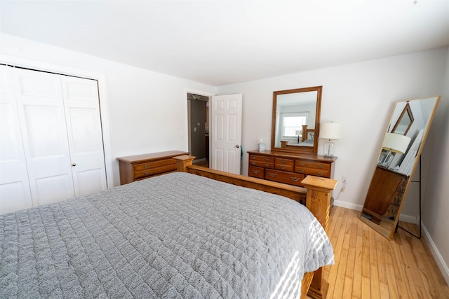 bedroom with a closet, baseboards, and light wood-style floors