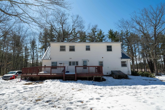 snow covered back of property featuring a wooden deck