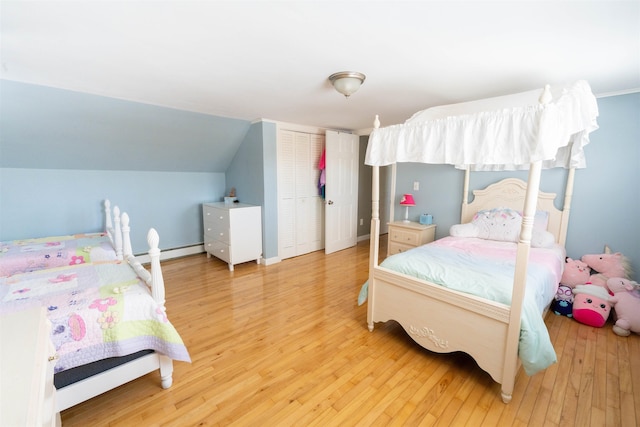 bedroom featuring a baseboard heating unit, hardwood / wood-style flooring, a closet, and lofted ceiling