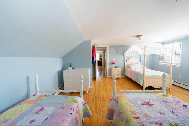 bedroom with a baseboard heating unit, lofted ceiling, baseboards, and wood finished floors