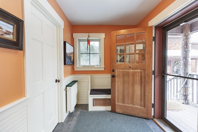 doorway to outside featuring a wainscoted wall and radiator heating unit