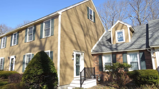 view of front of property with brick siding and a shingled roof