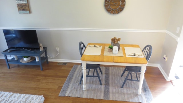 dining space with visible vents, wood finished floors, and baseboards