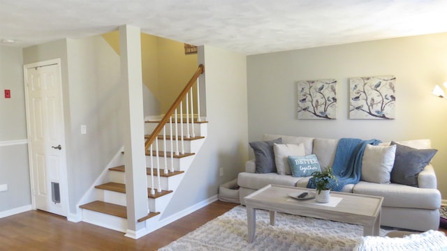 living room featuring baseboards, wood finished floors, and stairs