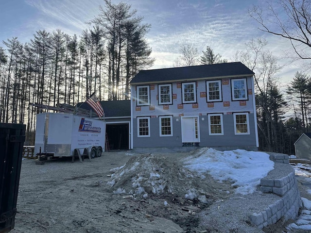 colonial home featuring gravel driveway and a garage