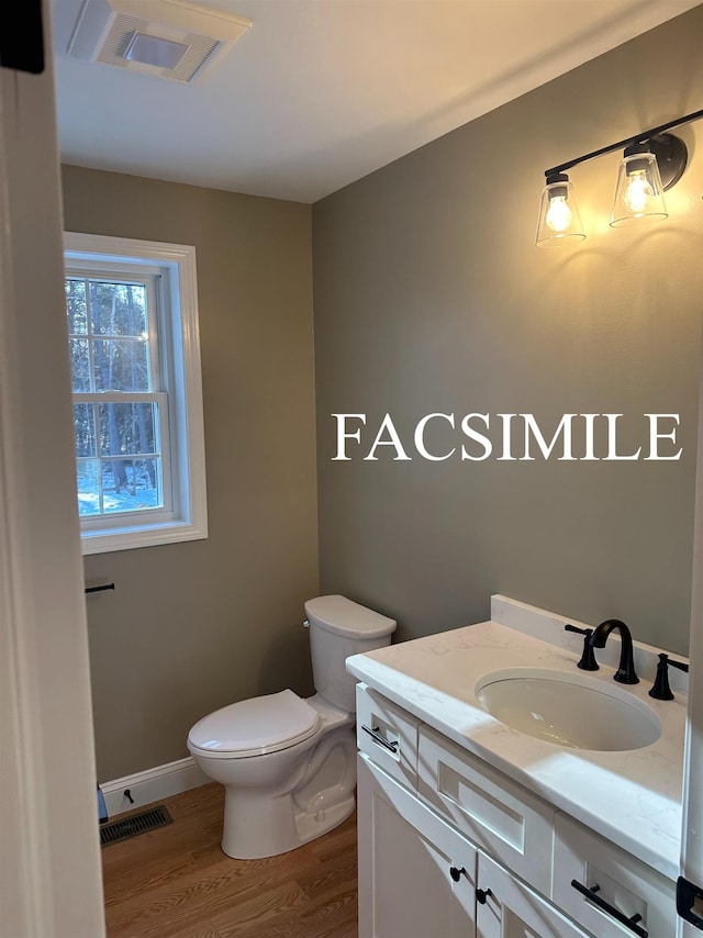 half bath featuring visible vents, toilet, wood finished floors, and vanity