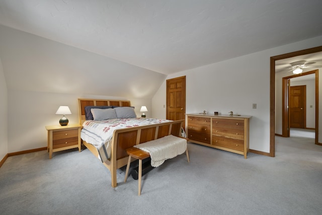 bedroom with vaulted ceiling, baseboards, and light carpet