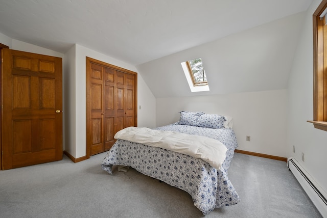 carpeted bedroom featuring lofted ceiling with skylight, baseboard heating, a closet, and baseboards