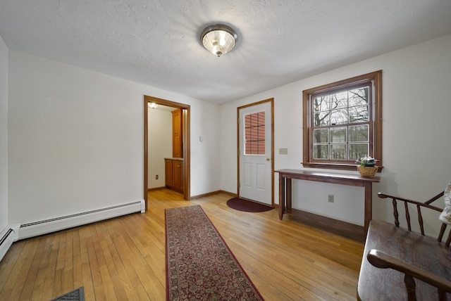 foyer entrance with baseboards, light wood-style floors, baseboard heating, and a textured ceiling