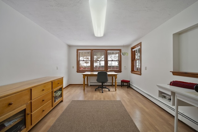 office area with a baseboard radiator, baseboards, light wood-type flooring, and a textured ceiling