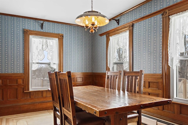 dining area featuring a baseboard radiator, a notable chandelier, and wallpapered walls