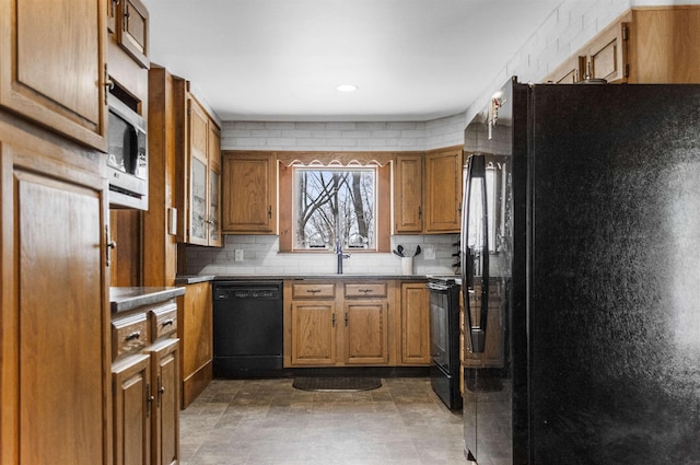 kitchen featuring brown cabinetry, black appliances, and tasteful backsplash