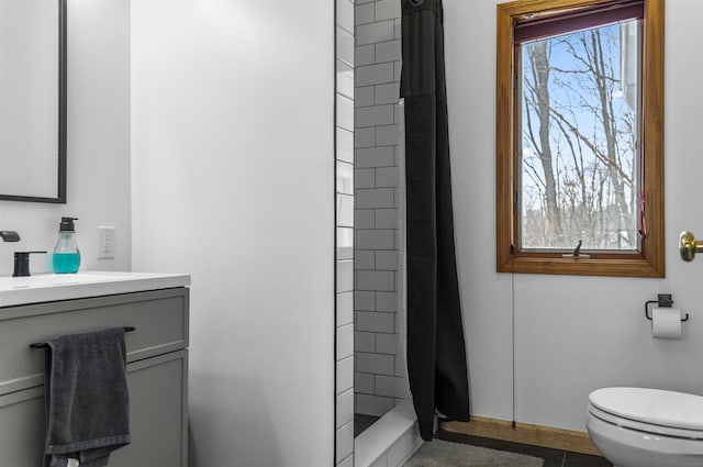 bathroom with vanity, toilet, baseboards, and a stall shower