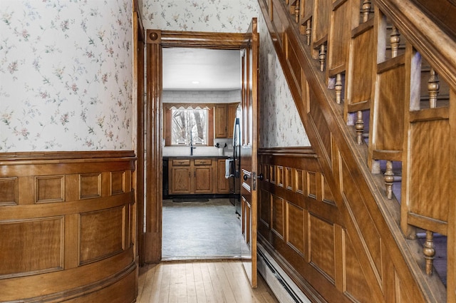 stairway featuring hardwood / wood-style floors, wainscoting, and wallpapered walls