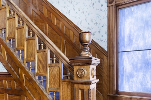 stairs with wainscoting and wallpapered walls