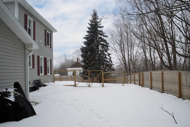 yard covered in snow with a fenced backyard