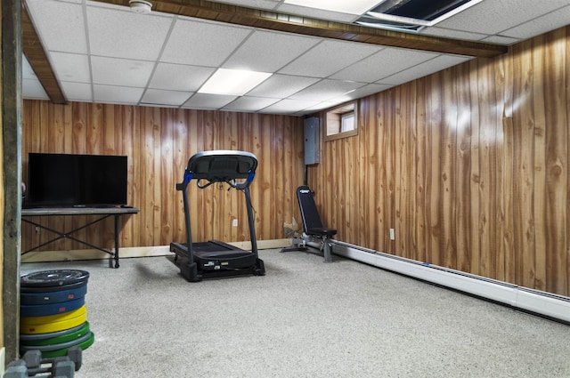 workout area featuring a baseboard heating unit, a drop ceiling, carpet flooring, and wood walls