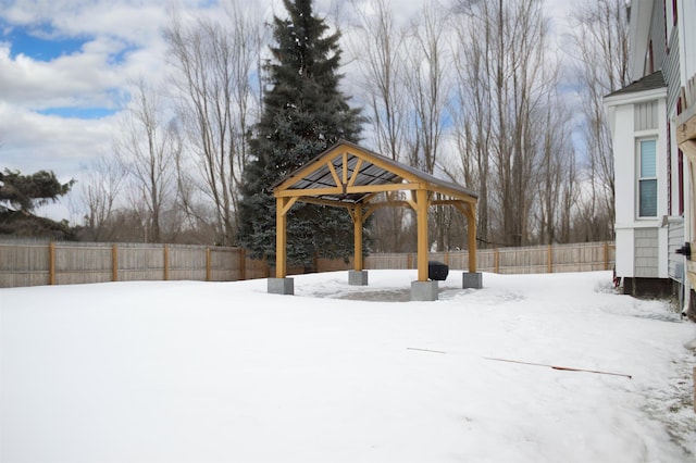 yard layered in snow with a gazebo and a fenced backyard