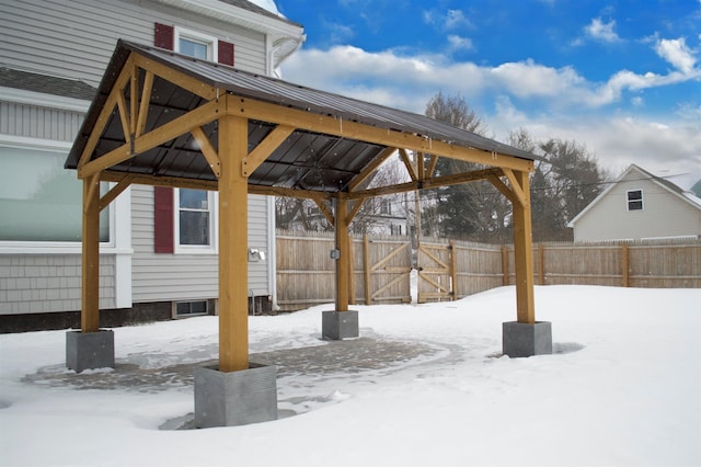 snowy yard featuring a gazebo and fence