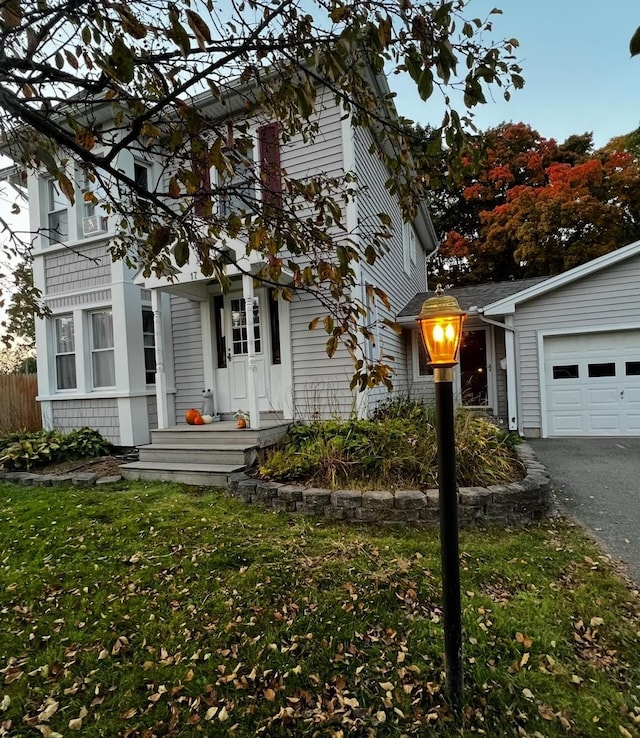 view of front facade featuring aphalt driveway, a garage, a front yard, and fence