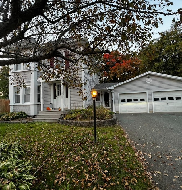 view of front of property with aphalt driveway, an attached garage, a front yard, and fence