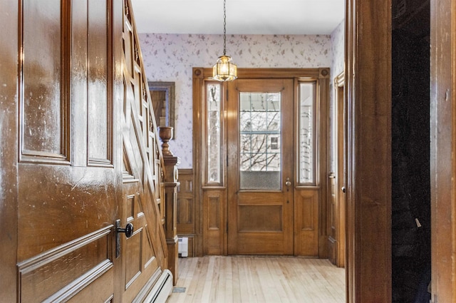 foyer featuring wainscoting, wallpapered walls, a baseboard heating unit, and light wood-style floors