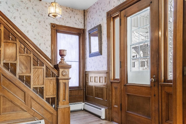 entrance foyer with light wood-type flooring, a wainscoted wall, a wealth of natural light, and wallpapered walls