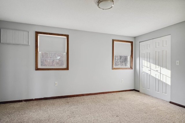 unfurnished bedroom with a closet, carpet flooring, a textured ceiling, and baseboards