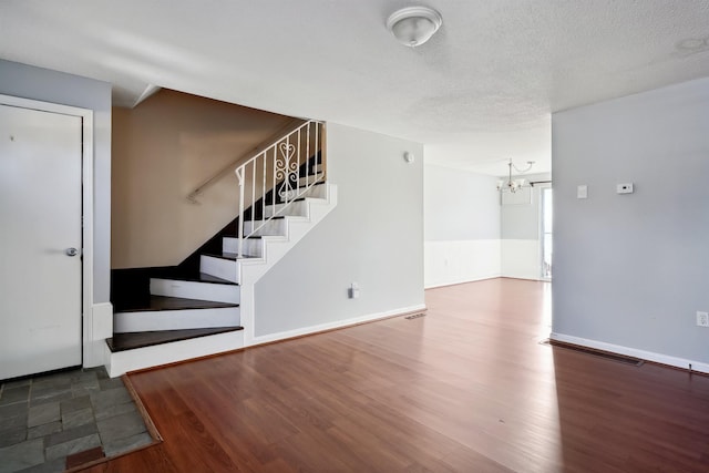 interior space featuring stairs, a notable chandelier, wood finished floors, and a textured ceiling