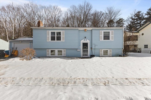 split foyer home with a detached garage, an outbuilding, and a chimney