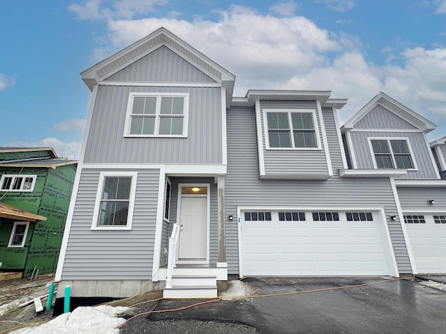 view of front of home featuring aphalt driveway, entry steps, a garage, and board and batten siding