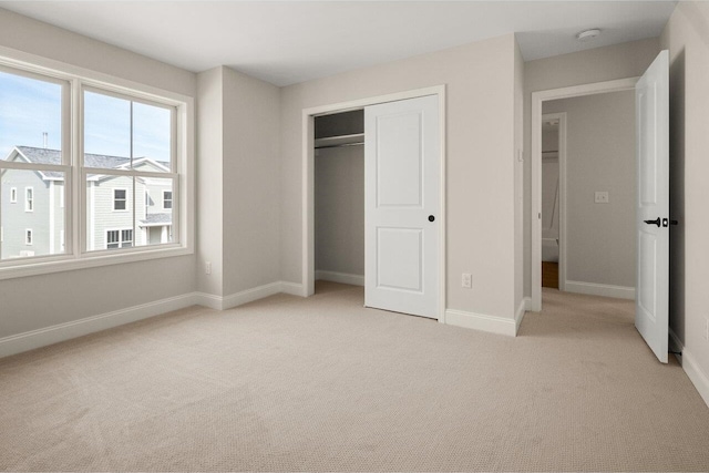 unfurnished bedroom featuring a closet, baseboards, and light colored carpet