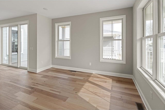 unfurnished room featuring baseboards, visible vents, and light wood finished floors