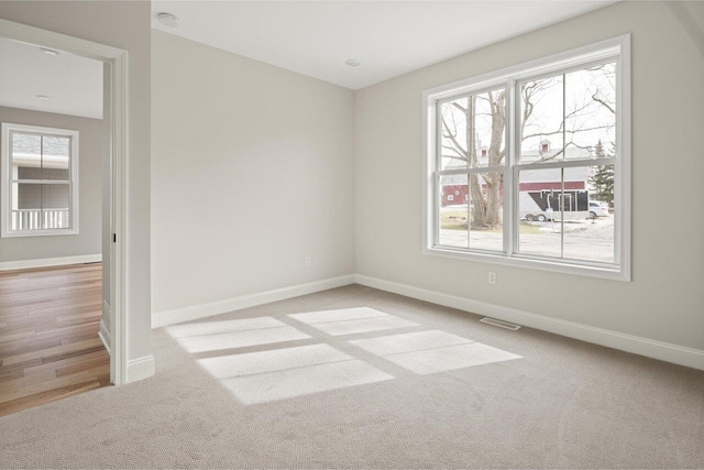 spare room featuring carpet flooring, plenty of natural light, and baseboards