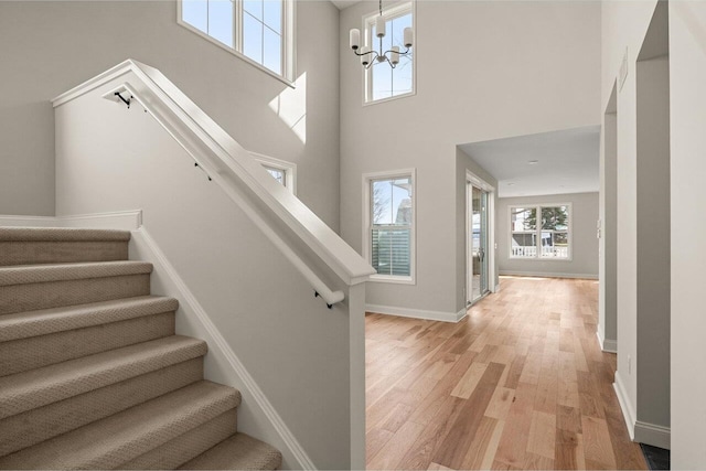 entryway with stairway, baseboards, a high ceiling, light wood-style floors, and a chandelier