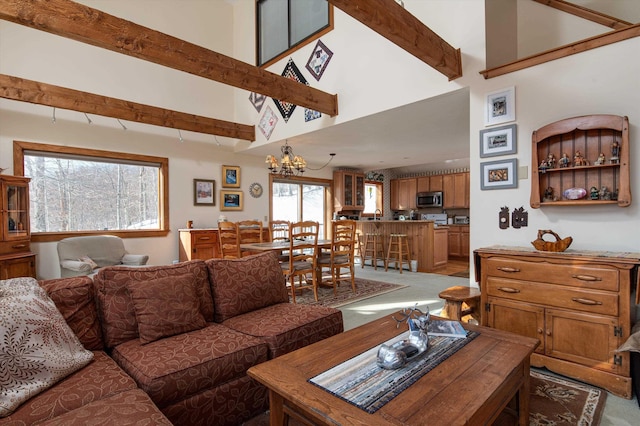 living room featuring an inviting chandelier, beam ceiling, light colored carpet, and a towering ceiling