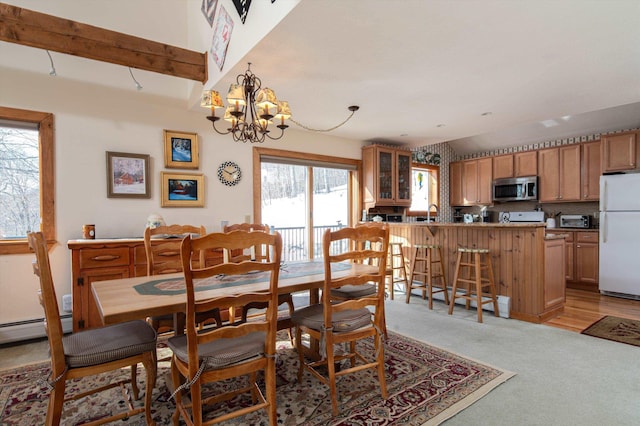 dining room featuring a chandelier, a toaster, light colored carpet, and lofted ceiling