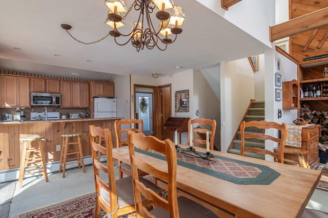 dining space with light carpet, a chandelier, and stairs