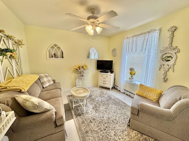 living area with baseboards and ceiling fan