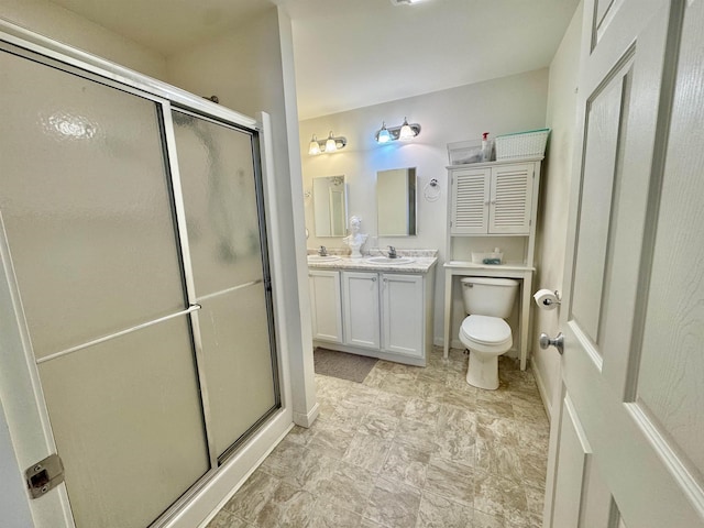 bathroom featuring double vanity, a shower stall, toilet, and a sink